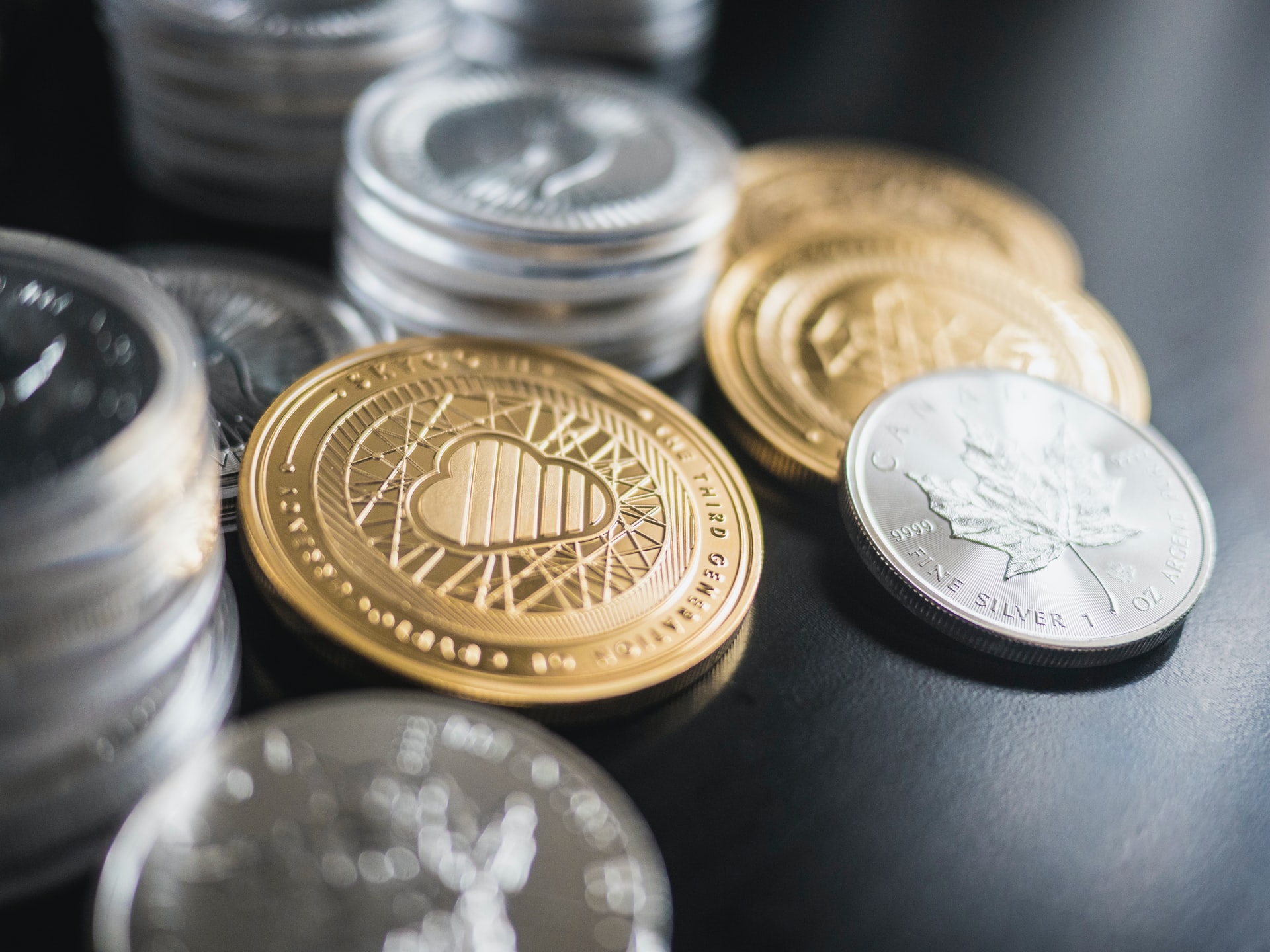 Close-up of gold and silver coins with the focus on a gold coin with a cloud symbol.